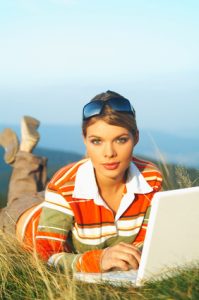 Young business woman relaxing, working on laptop computer on meadow